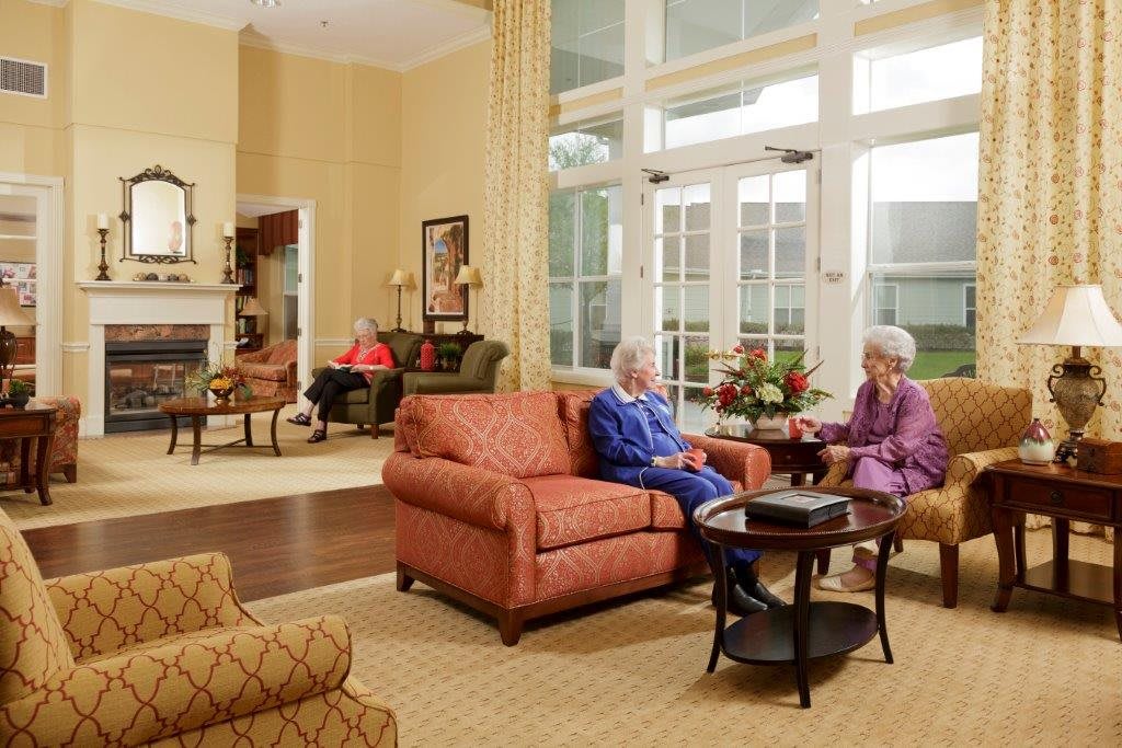Elderly individuals engaged in conversation in a cozy lounge area.