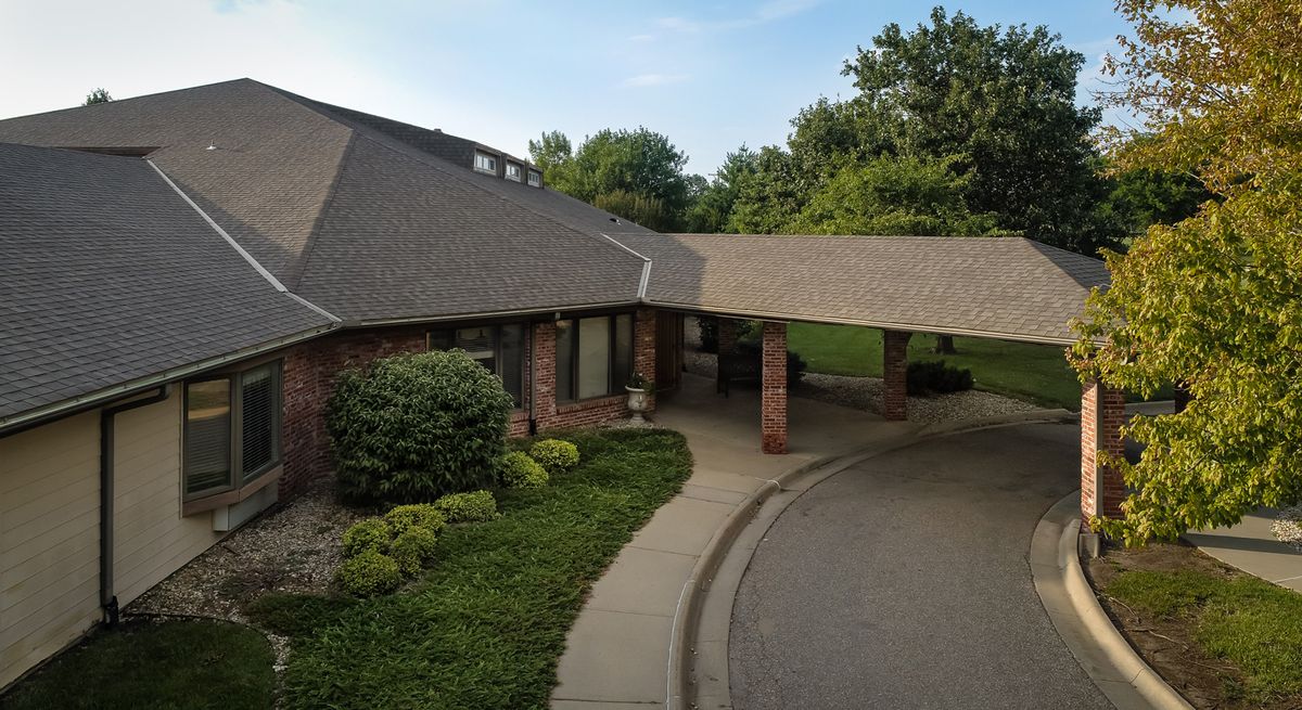 A one-story building with a covered driveway and well-maintained landscaping under a clear sky.