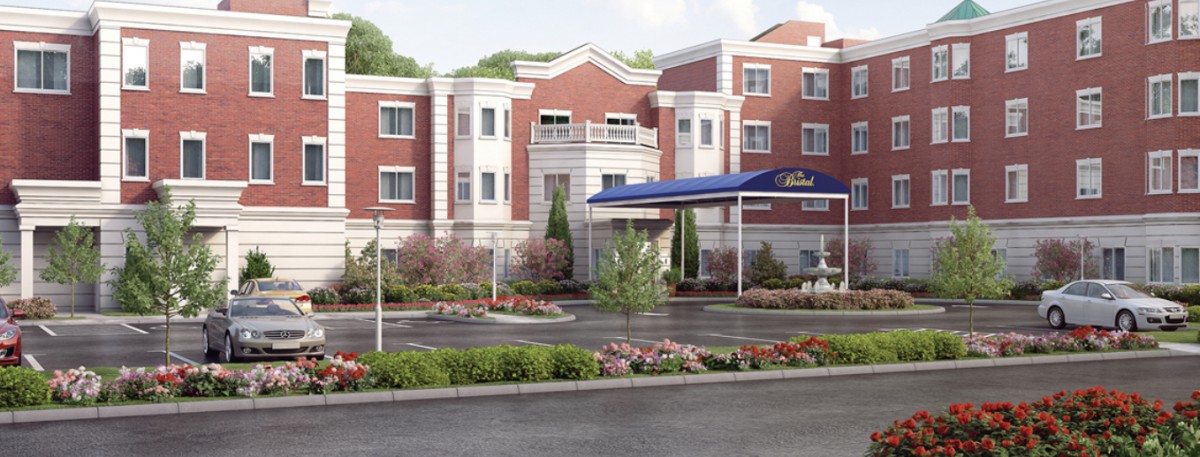 A modern hotel building with a well-maintained garden and entrance.
