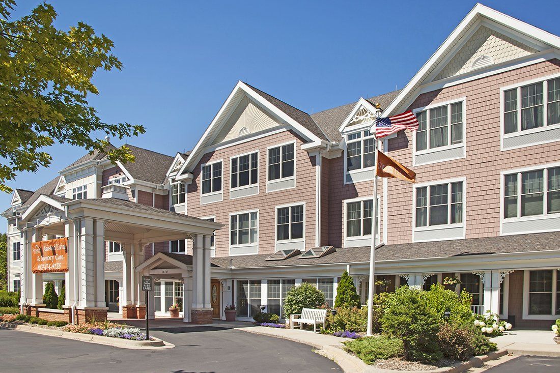 A multi-story residential building with an entrance and flags waving outside.