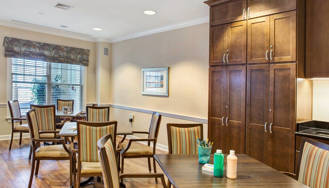 A dining area with wooden chairs, tables, a cabinet, and decorative elements.