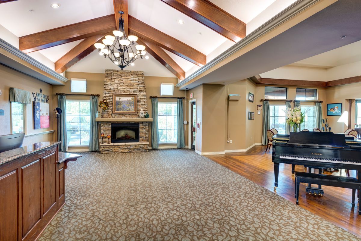 A spacious living room with a vaulted ceiling, featuring a fireplace and a grand piano.