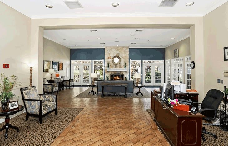 A spacious and elegantly decorated lobby area with a central fireplace and office desk.