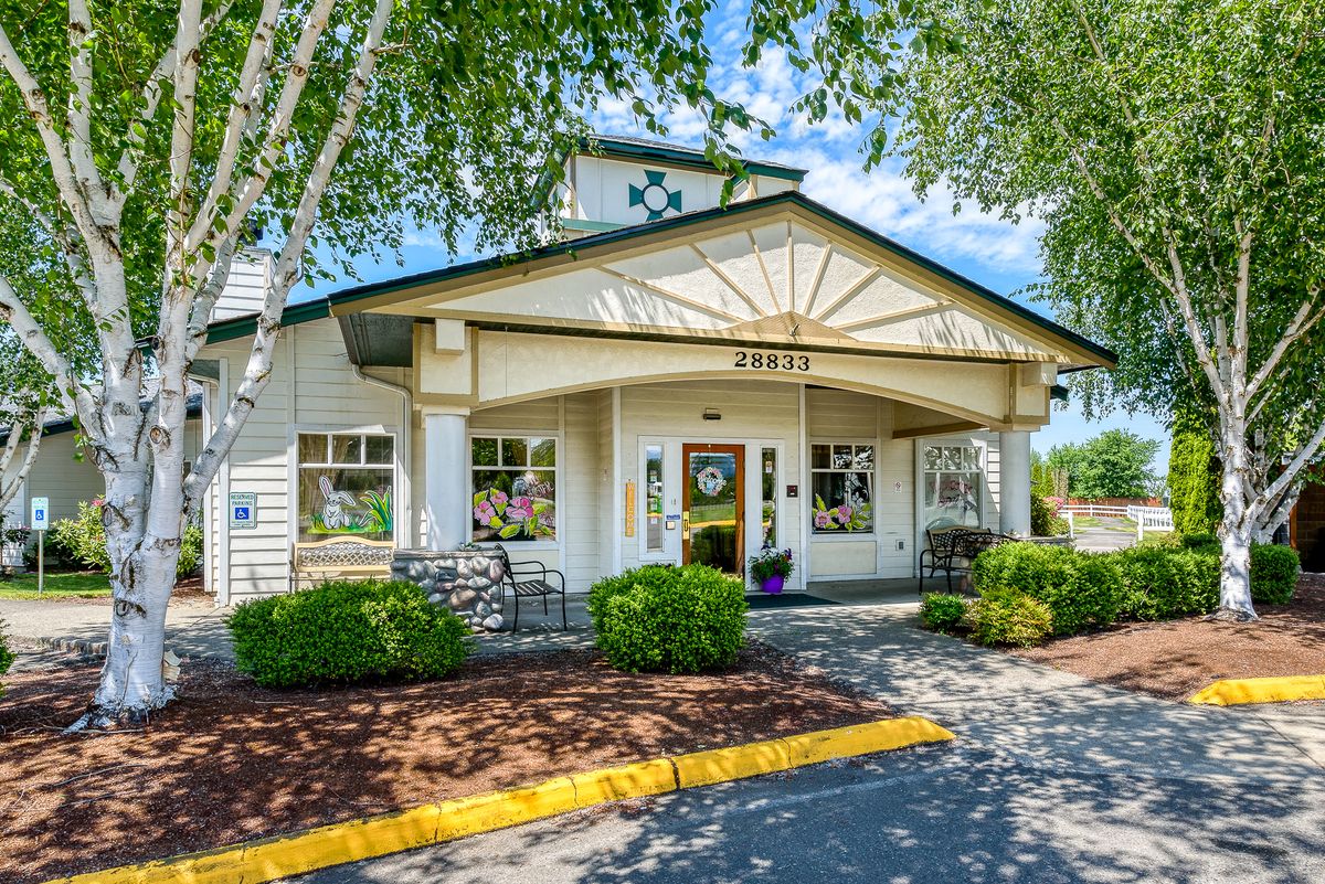 A charming building entrance surrounded by trees and bushes.