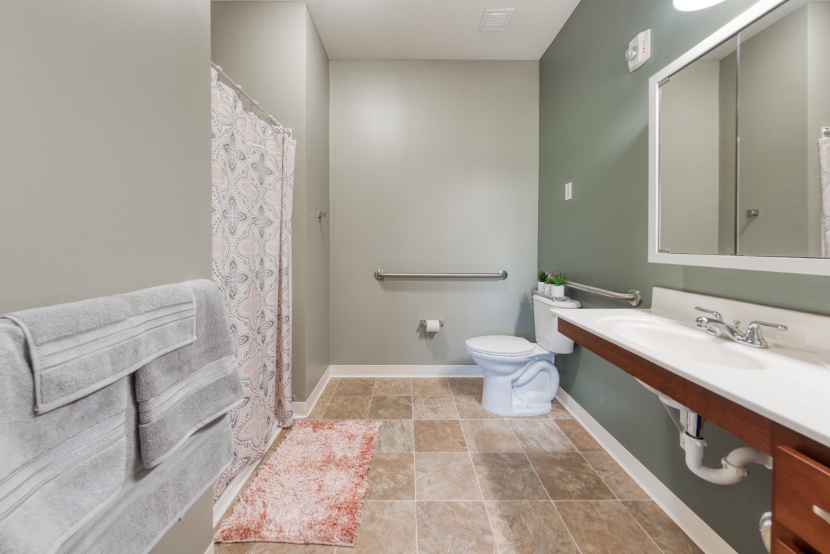 A spacious bathroom with a toilet, sink, and shower area.