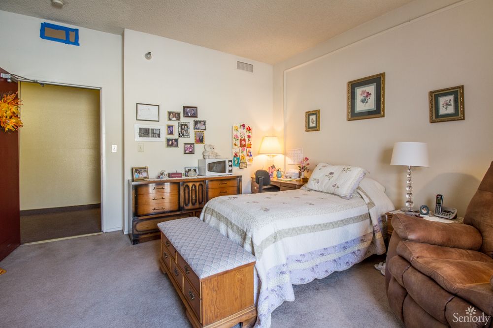 A cozy and well-decorated bedroom featuring a single bed, wooden furniture, and various wall decorations.