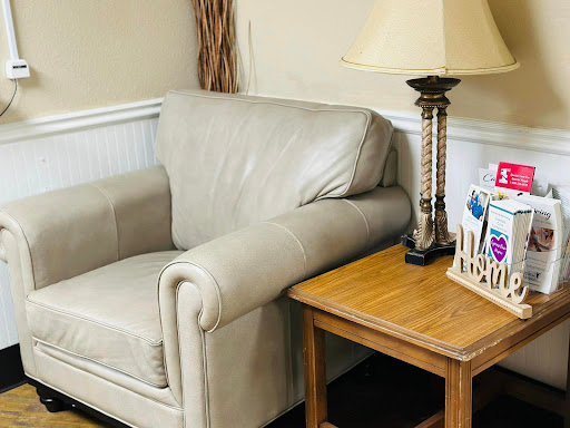 A cozy corner in a living room featuring a light-colored couch and a wooden table adorned with a lamp.