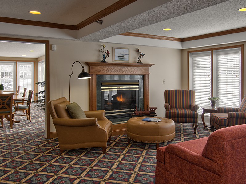 A cozy living room featuring a fireplace, comfortable armchairs, and a patterned carpet.