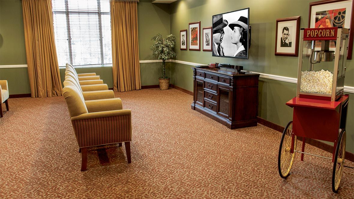 A cozy waiting room with chairs lined up, a television on the wall, and framed art pieces.