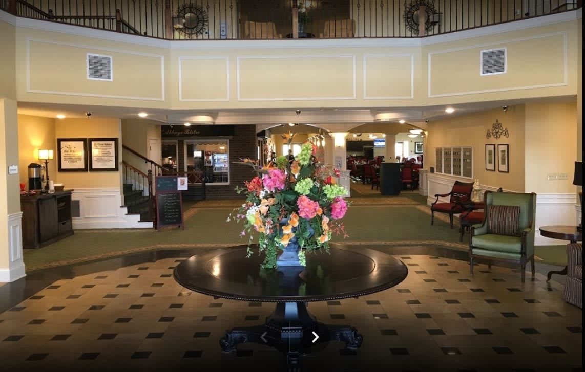 A hotel lobby with a flower arrangement on a central table.
