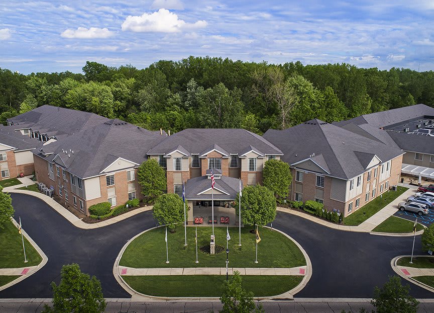 Aerial view of a residential building surrounded by trees and a driveway.