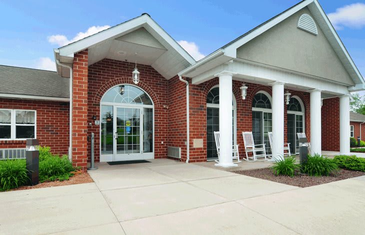 A brick building entrance with large glass doors and white columns.