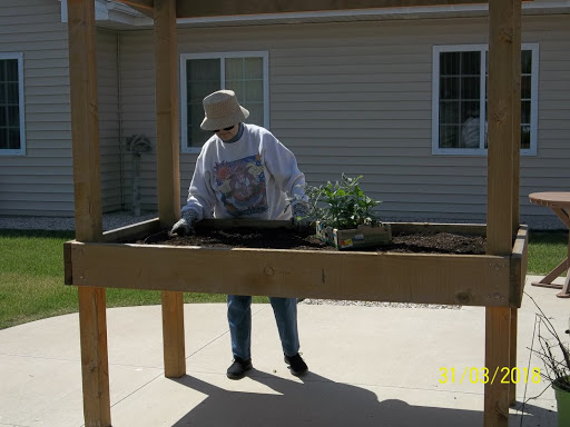 A person engaging in gardening activities at a raised bed, enjoying the outdoors.