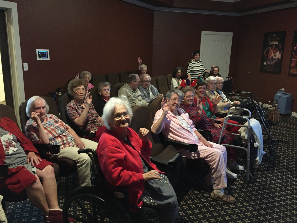 A group of seniors gathered in a small theater, ready to enjoy a movie or presentation.