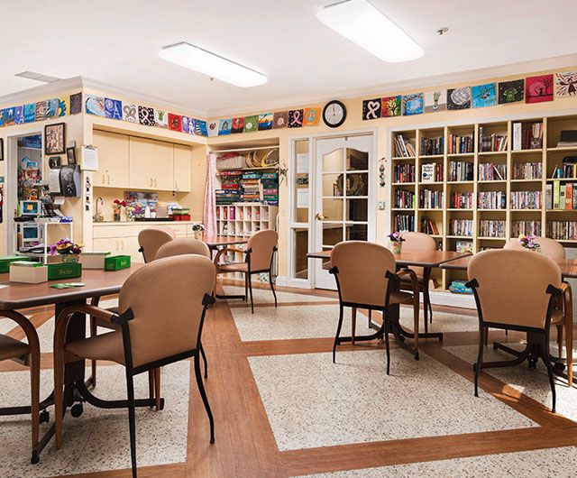 A cozy library with bookshelves, tables, and chairs arranged for reading.