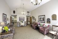 A cozy living room with plush chairs, a chandelier, and wall art.