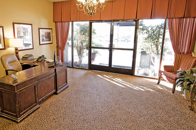 A well-lit office with a wooden desk, large windows, and elegant decor.