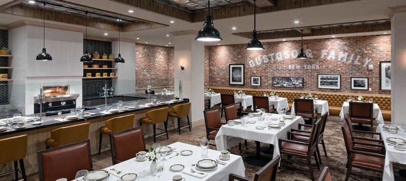 A cozy restaurant dining area with neatly set tables and a warm brick wall decor.