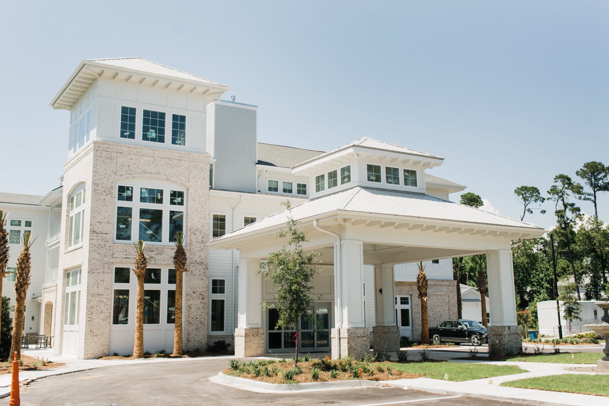 A modern building with a covered entrance and surrounding palm trees.