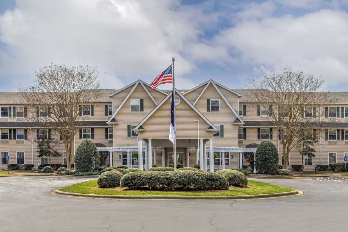 A residential building with flags flying out front and neatly maintained landscaping.