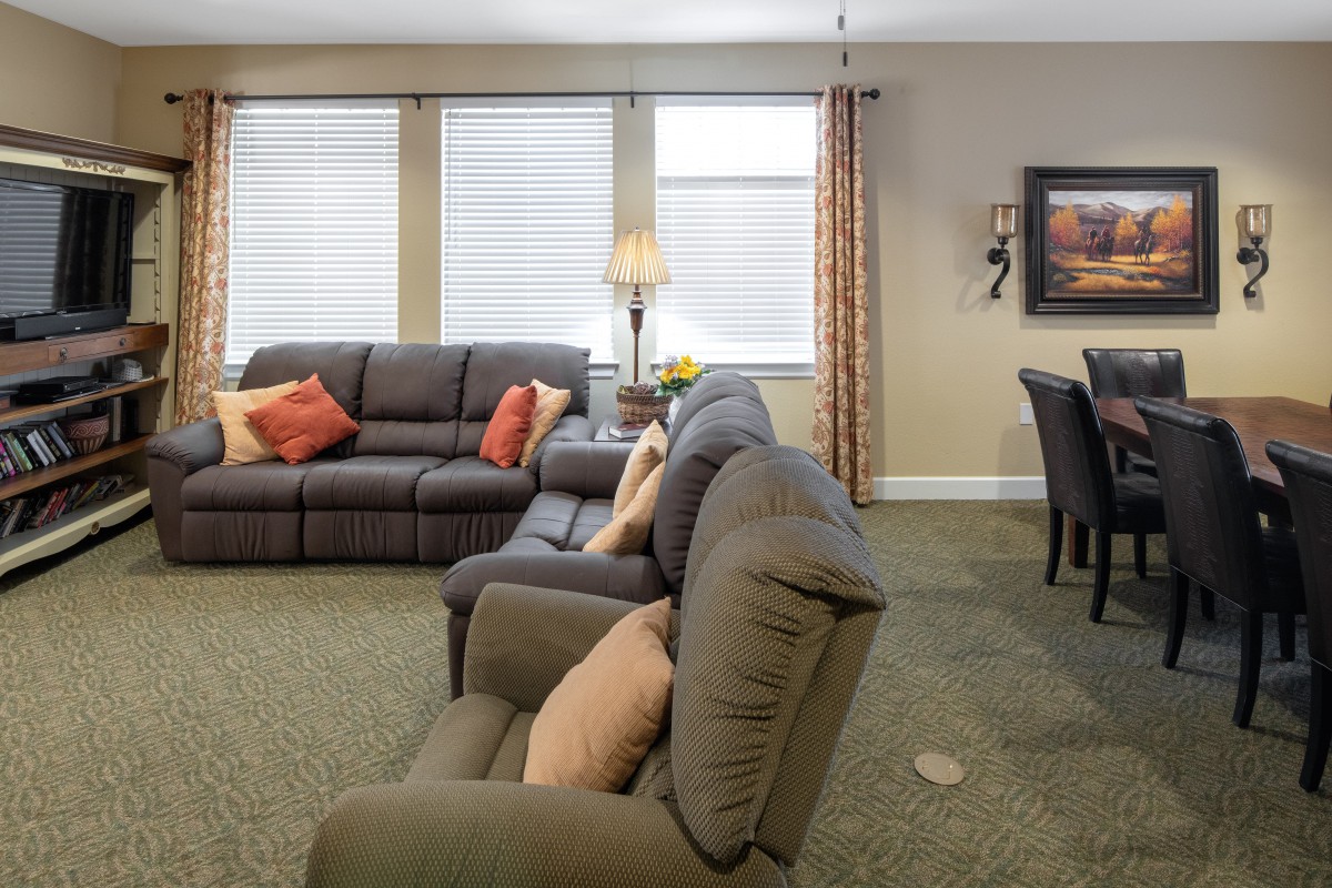 A cozy living room with comfortable sofas and a dining area in the background.