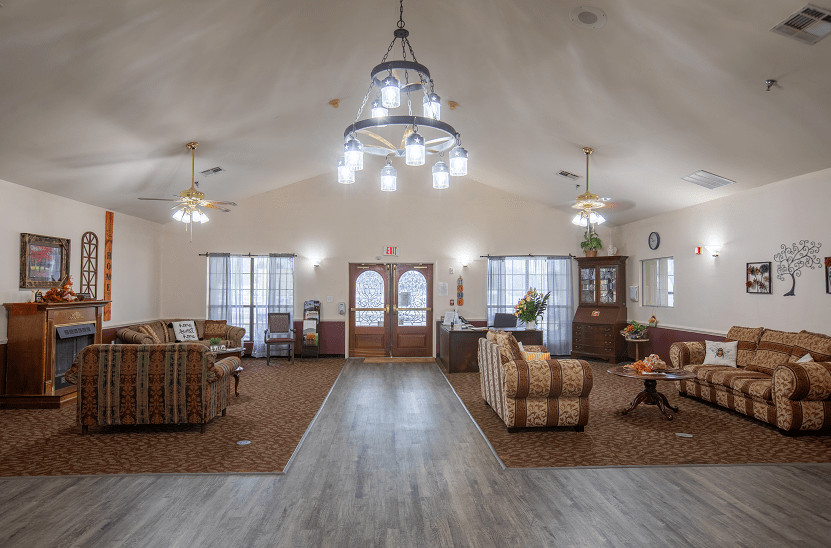 A spacious living room with elegant chandeliers, comfortable sofas, and wooden flooring.