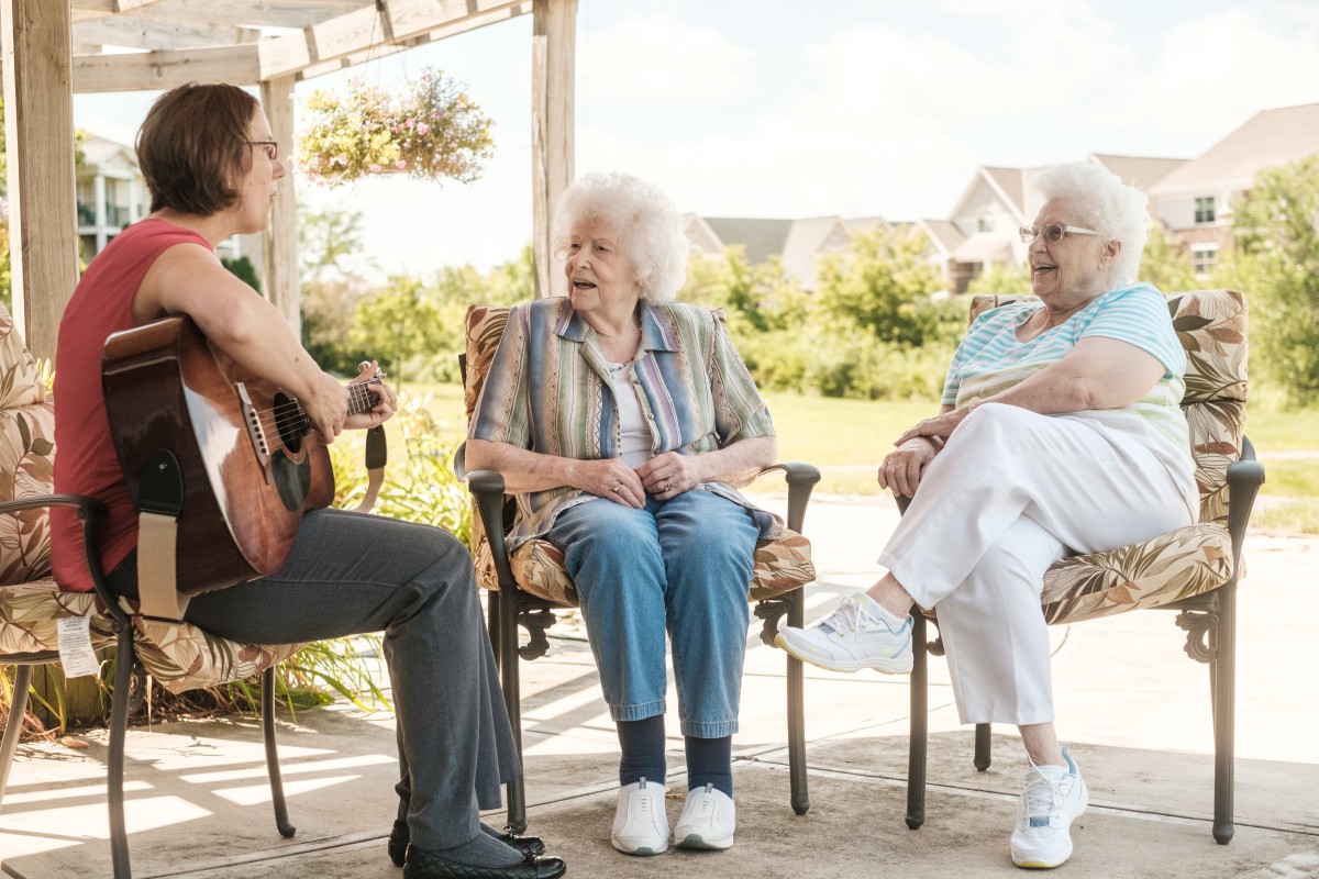 A group of seniors enjoying a conversation and music outdoors.