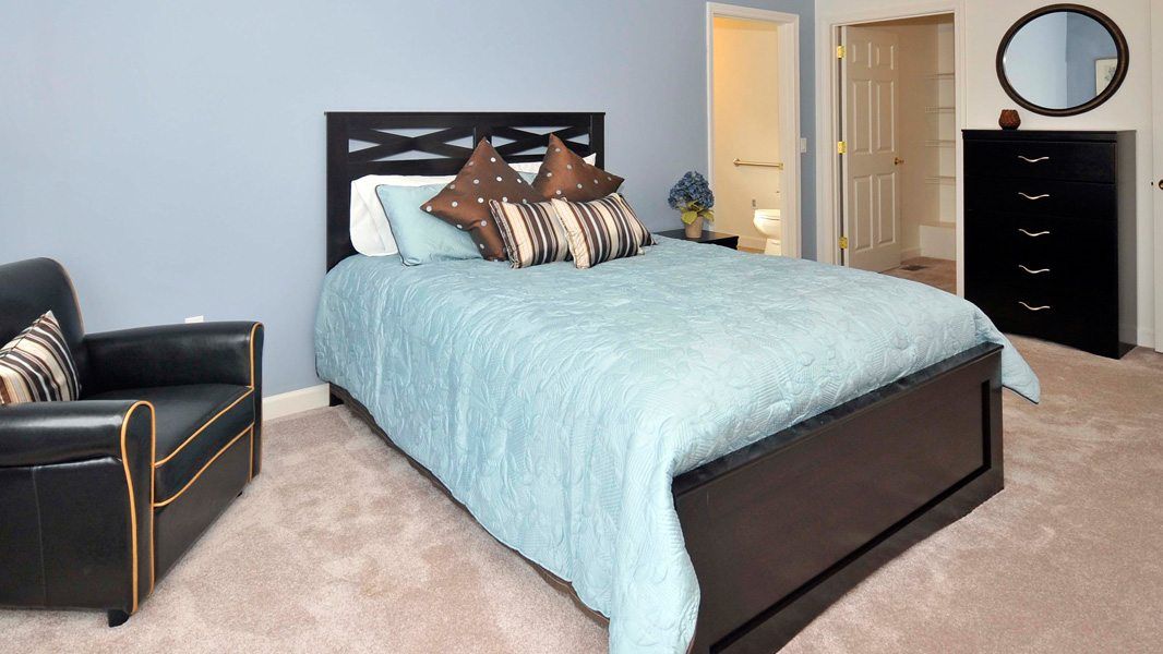 A cozy bedroom with a neatly made bed and stylish pillows.