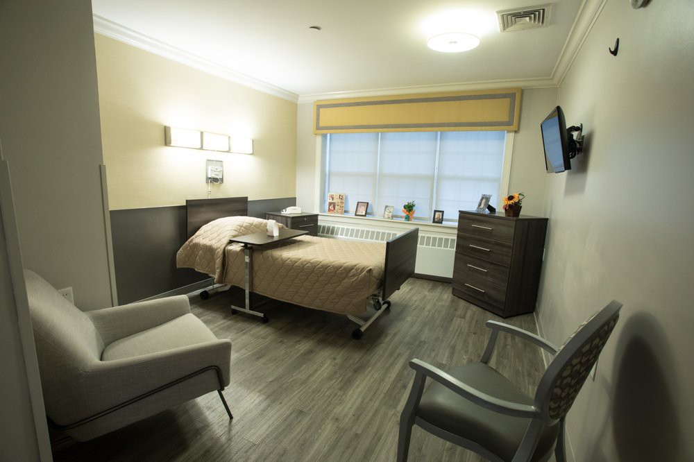 A clean and well-equipped hospital room with a bed, chairs, and a television.