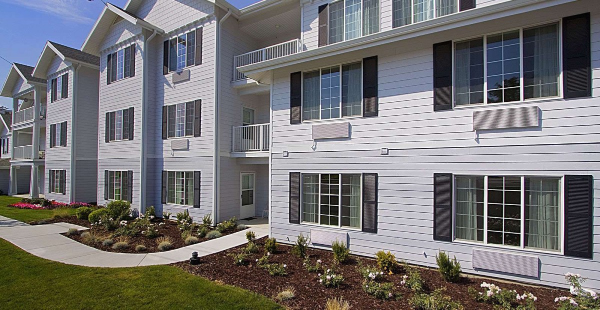 Modern apartment building with balconies and landscaped garden.