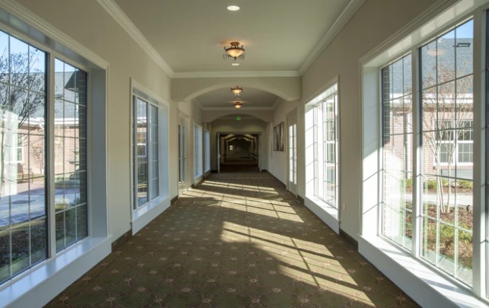 A well-lit hallway with large windows and a carpeted floor.