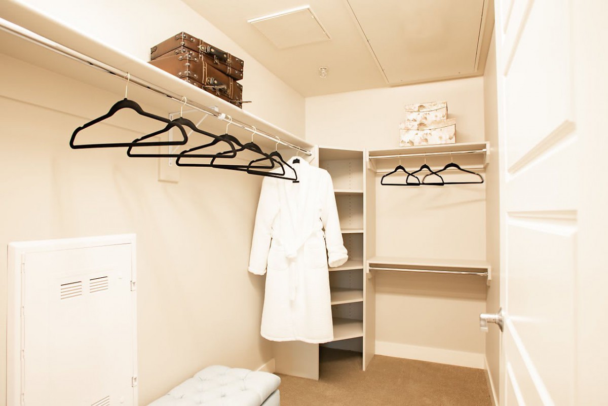 A spacious walk-in closet featuring hangers, a robe, and organized storage shelves.