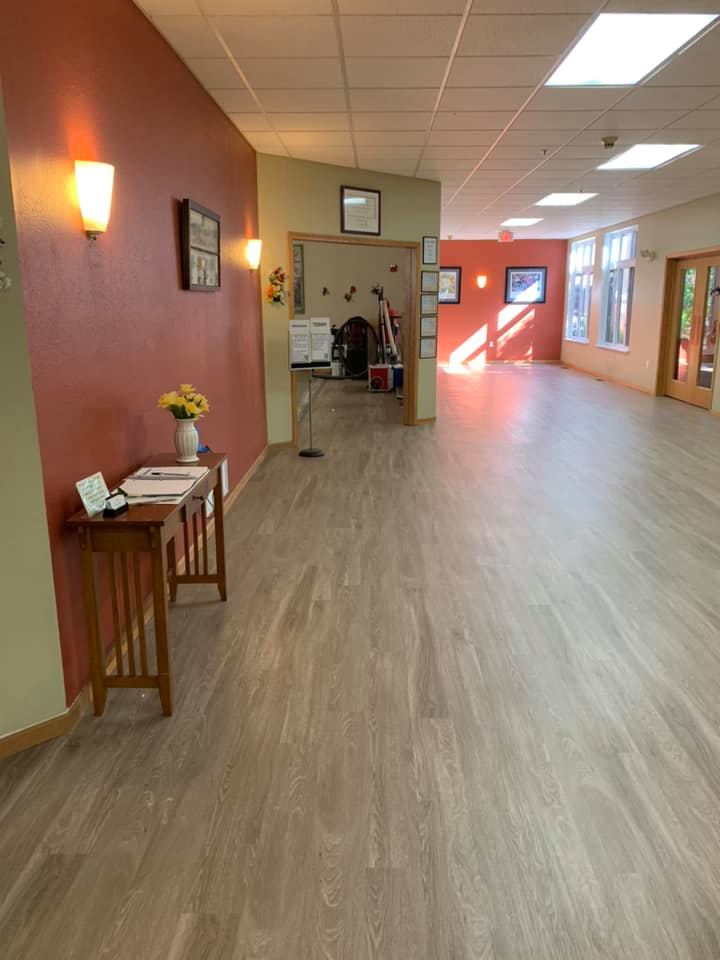 A spacious hallway with wooden flooring and vibrant red walls, leading to a reception area.