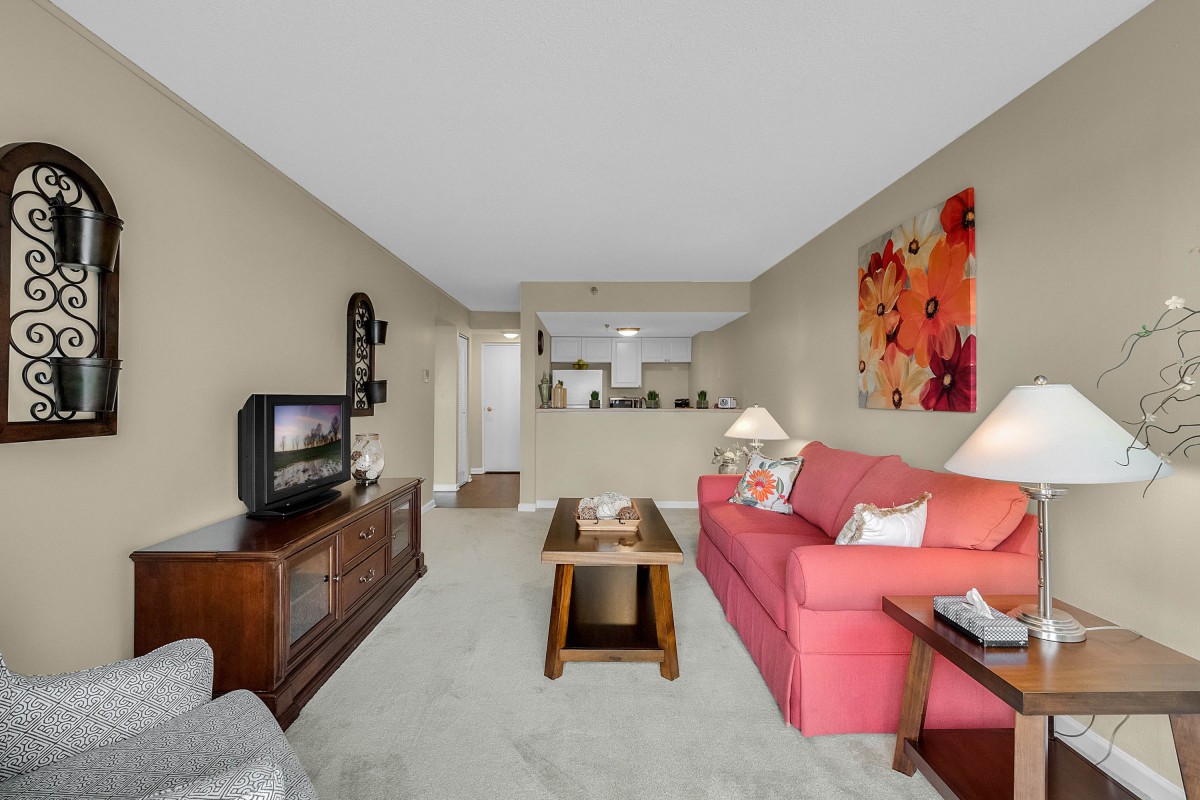 A cozy living room with a red sofa, wooden furniture, and colorful artwork.