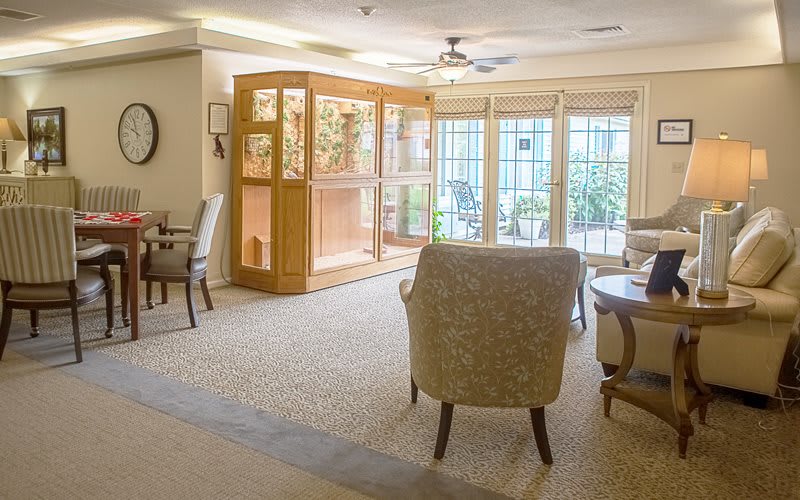 A cozy and well-lit living room with comfortable chairs and large windows.