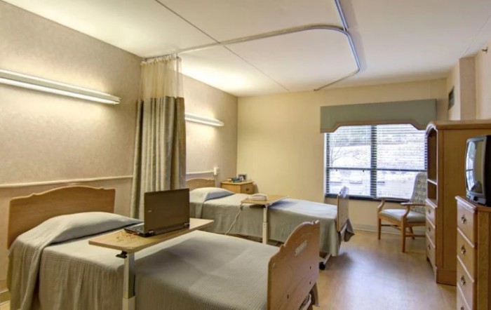 A hospital ward with multiple beds separated by curtains.