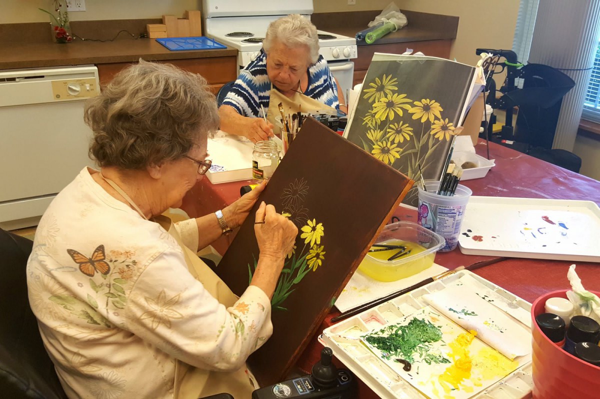 Seniors enjoying a painting class, focusing on creating floral artwork.