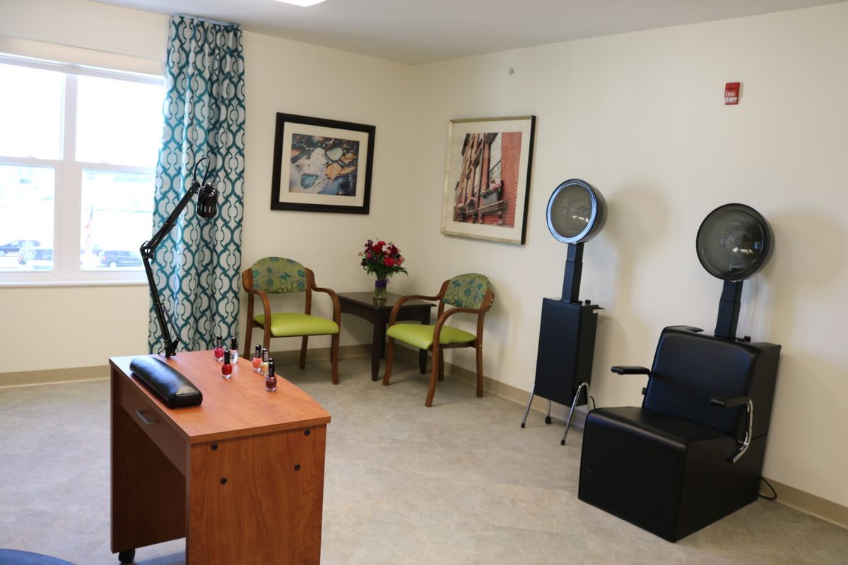 A cozy hair salon interior featuring seating, hair dryers, and wall art.
