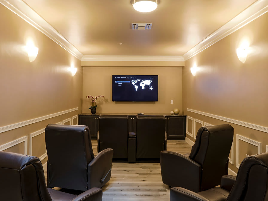 A cozy home theater room with recliner chairs and a large screen.