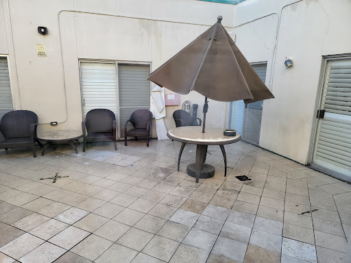 A quiet outdoor patio area featuring a table with an umbrella and chairs, surrounded by tiled flooring.