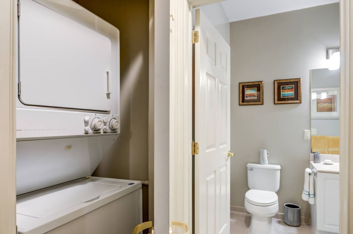 A combined laundry and bathroom space featuring a washer, dryer, and toilet.