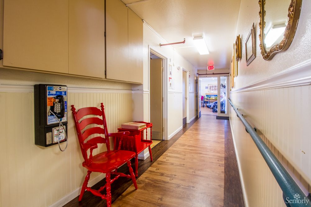 A brightly lit hallway featuring a red chair and wooden flooring.