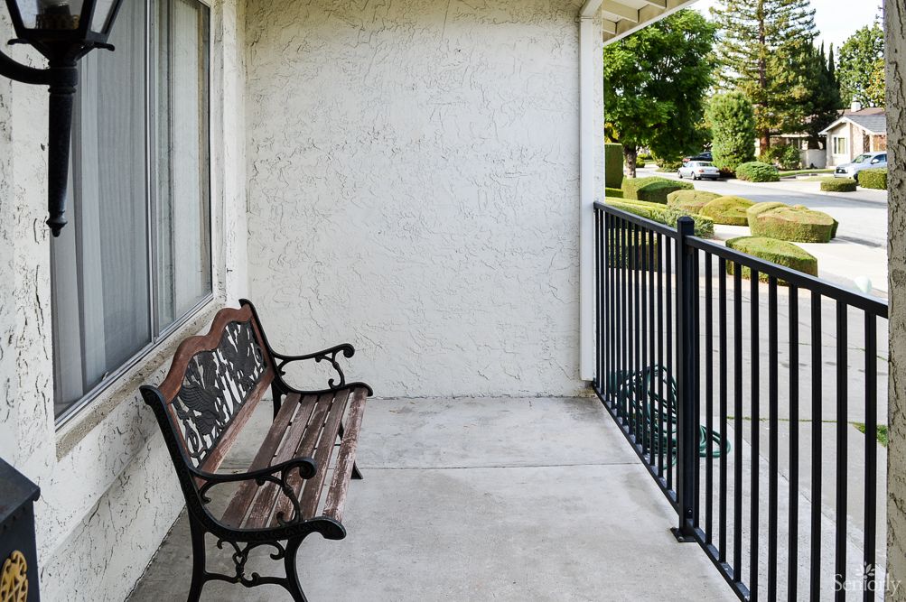 A quiet balcony with a wooden bench and metal railings.