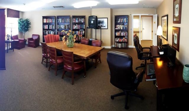A cozy library and meeting room with bookshelves, a wooden table, and comfortable chairs.