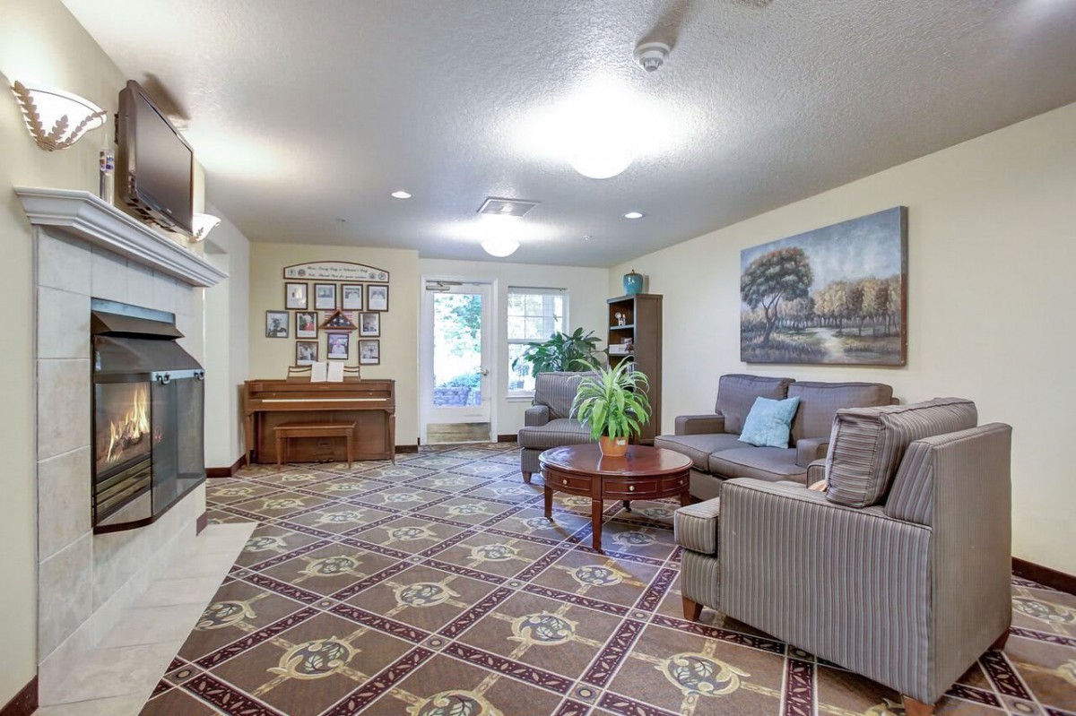 A cozy living room with a sofa, coffee table, and piano, featuring decorative art and a patterned rug.