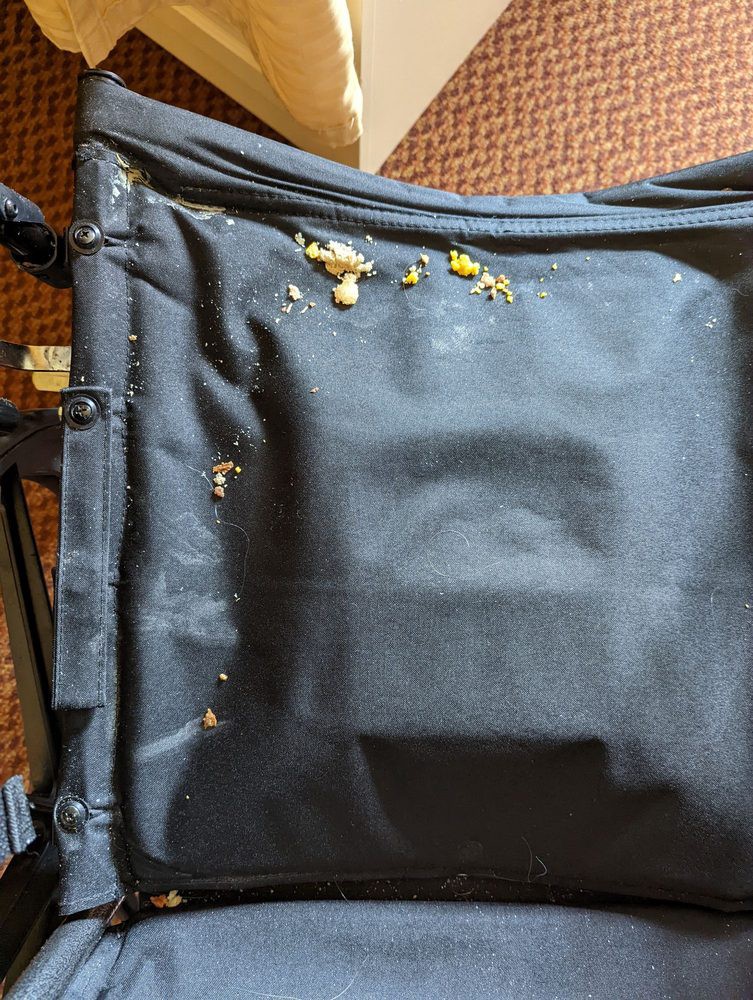 A black suitcase with visible damage and stains on the fabric surface.