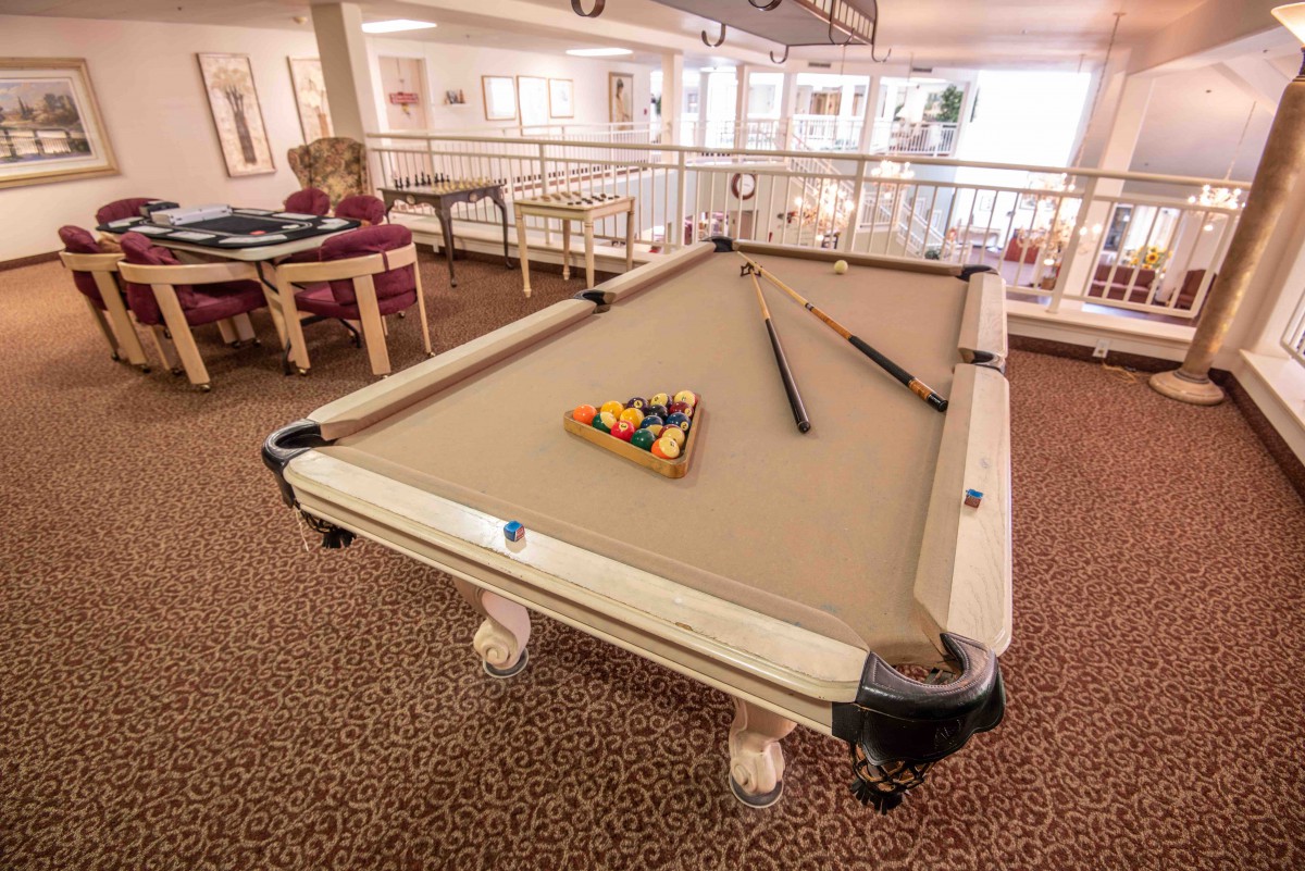 A pool table set up in a spacious game room with cues and racked balls ready for play.