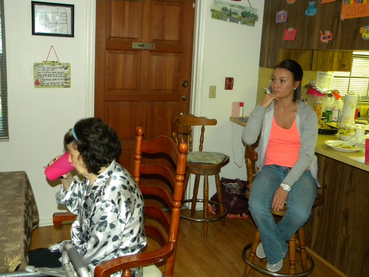 A child and an adult sitting indoors, with the child drinking from a pink cup.