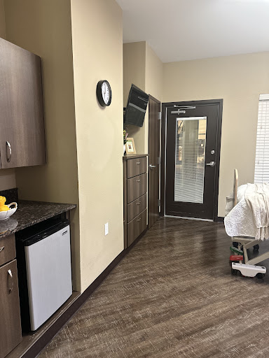 A modern interior featuring a kitchenette, clock, and door leading to the outside.