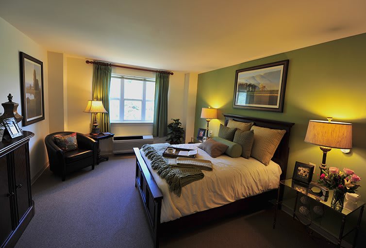 A cozy bedroom with a neatly made bed, ambient lighting, and elegant decor.